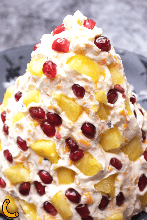 Pineapple and pomegranate seeds placed in Christmas tree cheese ball